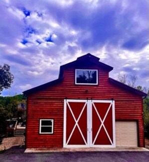 A red barn with two large white doors and a small window on the front.