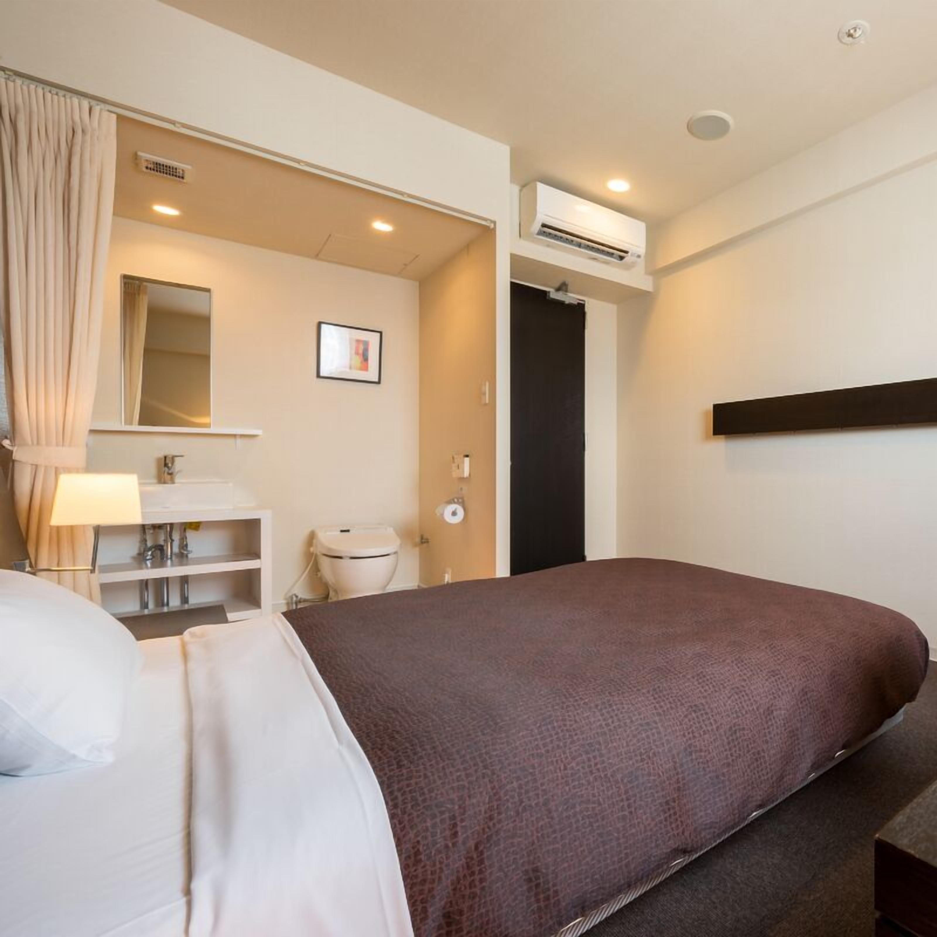 Une chambre d’hôtel équipée d’un lit, d’une salle de bain, d’un miroir et d’un appareil de climatisation.