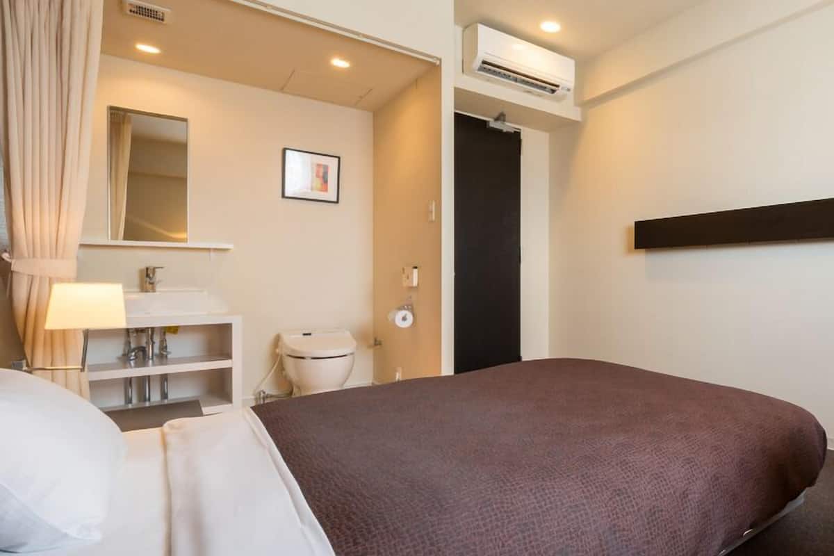 Une chambre d’hôtel équipée d’un lit, d’une salle de bain, d’un miroir et d’un appareil de climatisation.
