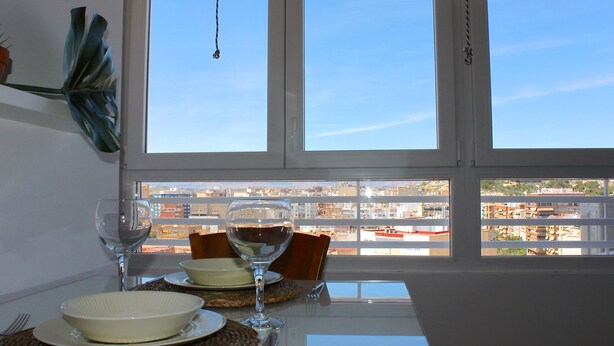 Ein Esstisch mit Tellern, Schüsseln und Weingläsern, vor einem Fenster mit Blick auf eine Stadtlandschaft.