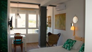 Ein Hotelzimmer mit Bett, Schreibtisch mit Stuhl, einer Karte an der Wand und einem Fenster mit Jalousien.