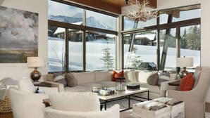 A cozy living room with a large window overlooking a snowy mountain landscape. - Big Sky Vacation Rentals: Silvertip 22 Alpine Bend (big sky)