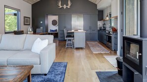 A modern kitchen with a central island, a dining area with a bench, and a living room with a sofa and coffee table.