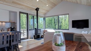 A modern kitchen with a large window, a built-in stove, and a dining area with a wooden table.
