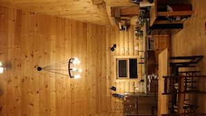 A wooden cabin interior with a sauna, a kitchen area, and a dining space. - Jackson, NH Log Cabin near Storyland in White Mountains: 2Queen Bdrms+Sleep Loft (Jackson)