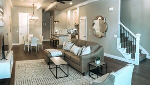 A spacious living room with a sofa, coffee table, and a dining area with chairs and a table.