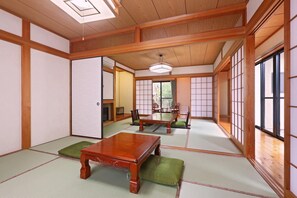 Une pièce de style japonais traditionnel, avec un sol recouvert de tatamis, une table en bois et des portes coulissantes.