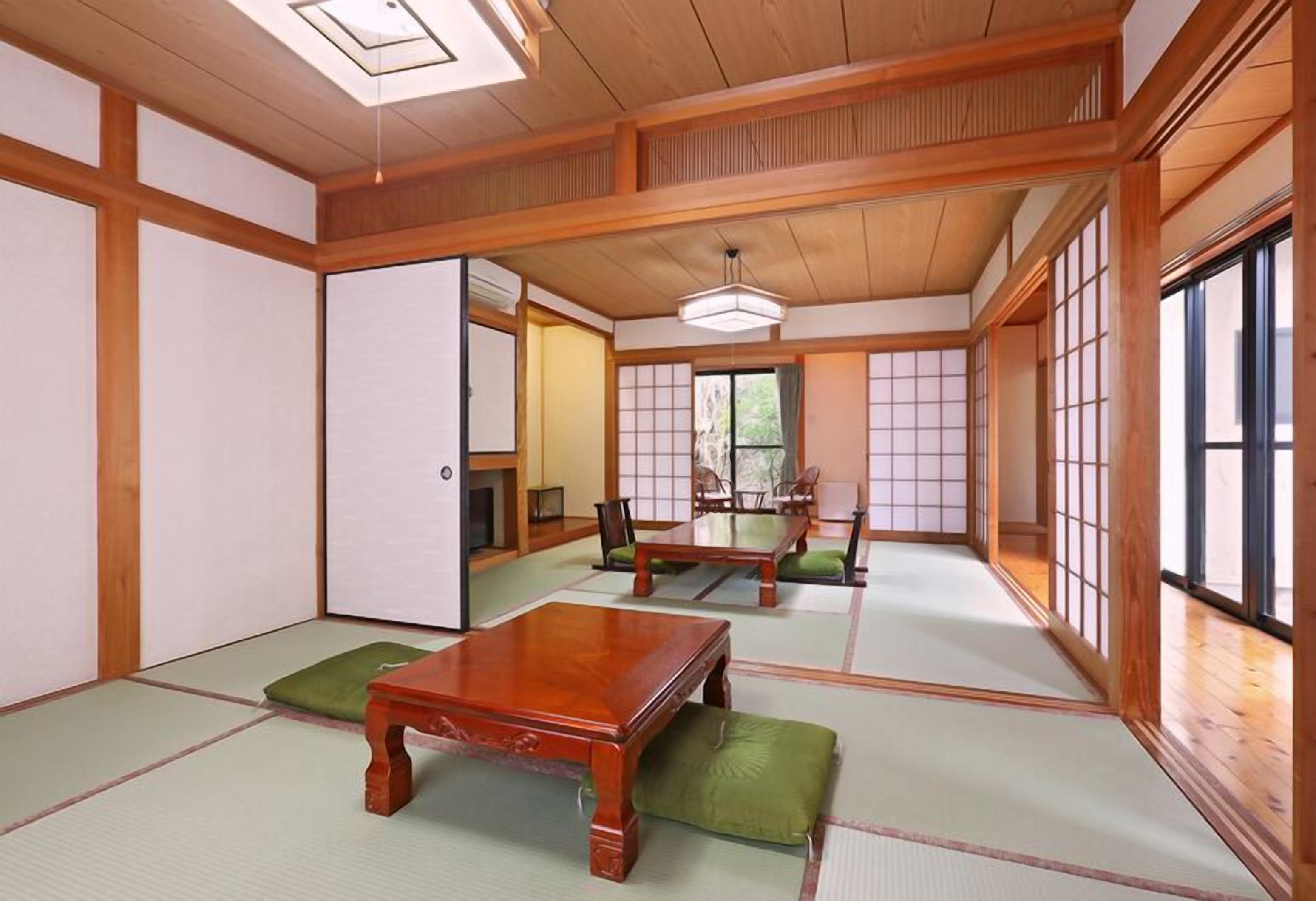 A traditional Japanese room with tatami flooring, wooden furniture, sliding doors, and a view of the outdoors.