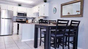 A modern kitchen with white cabinets, stainless steel appliances, and a dining area with a dark wooden table and chairs.