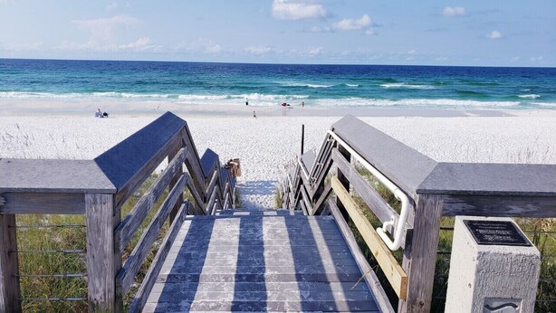 A wooden boardwalk leading to a beach with white sand and the ocean in the background. - Great location, few steps from the beach!!! (Miramar Beach)