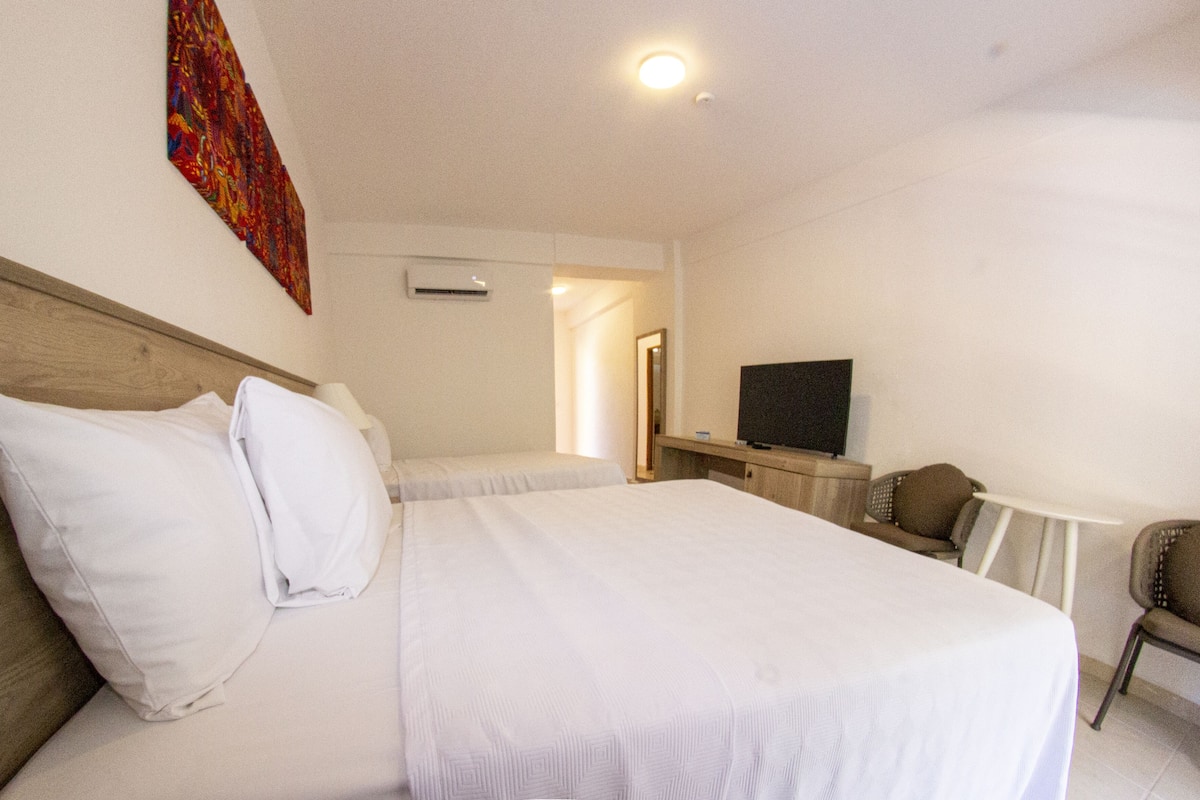 A hotel room with a large bed, a television, and a small desk.