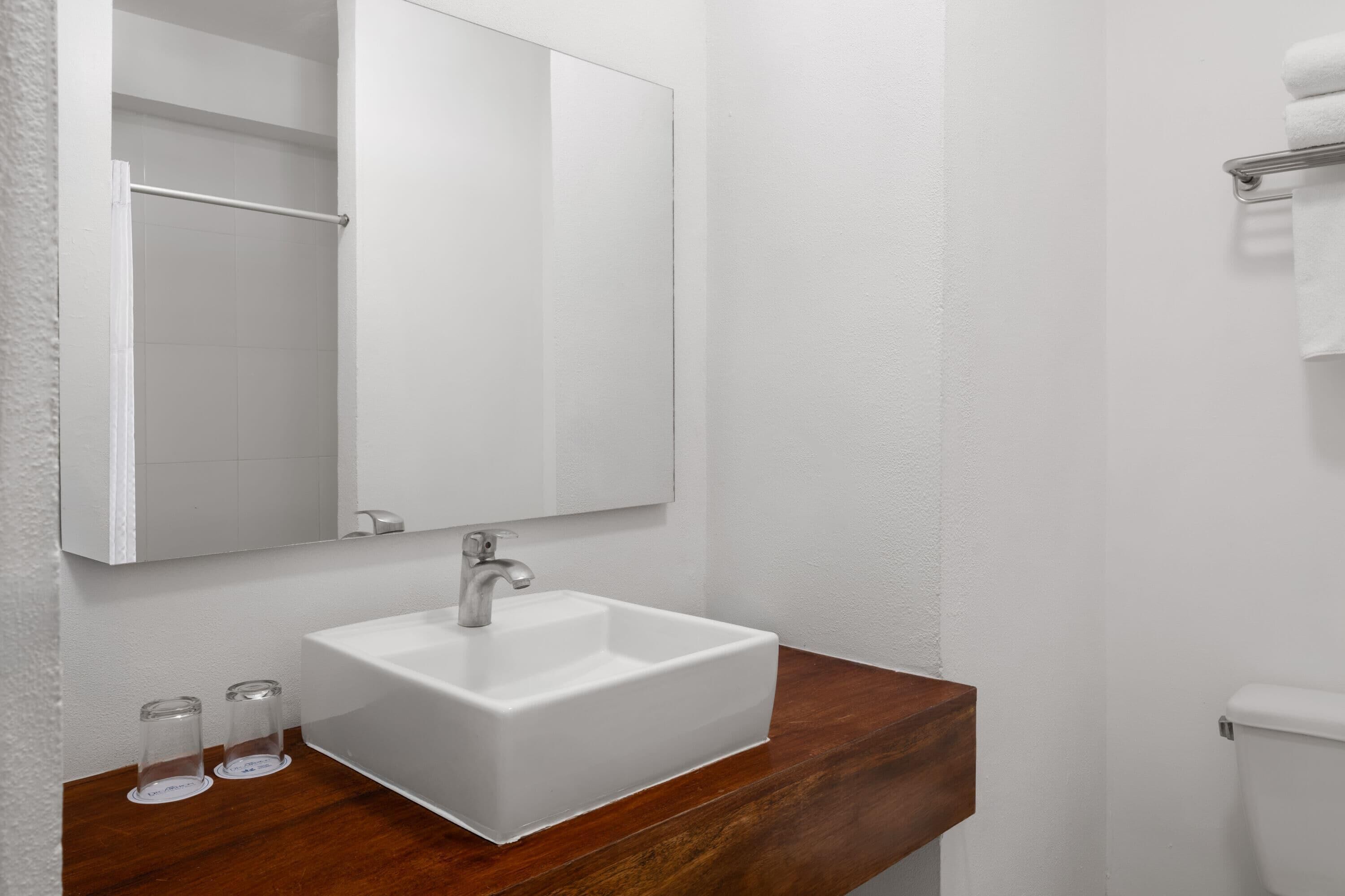Un baño con un lavamanos blanco, encimera de madera y un espejo sobre el lavamanos.