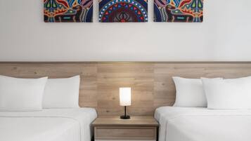 A hotel room with two single beds, a nightstand with a lamp, and a wooden headboard.