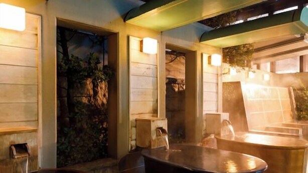 An outdoor seating area with stone walls and wooden benches. - Tennen Onsen Relax Park Terume Kanazawa (Kanazawa)