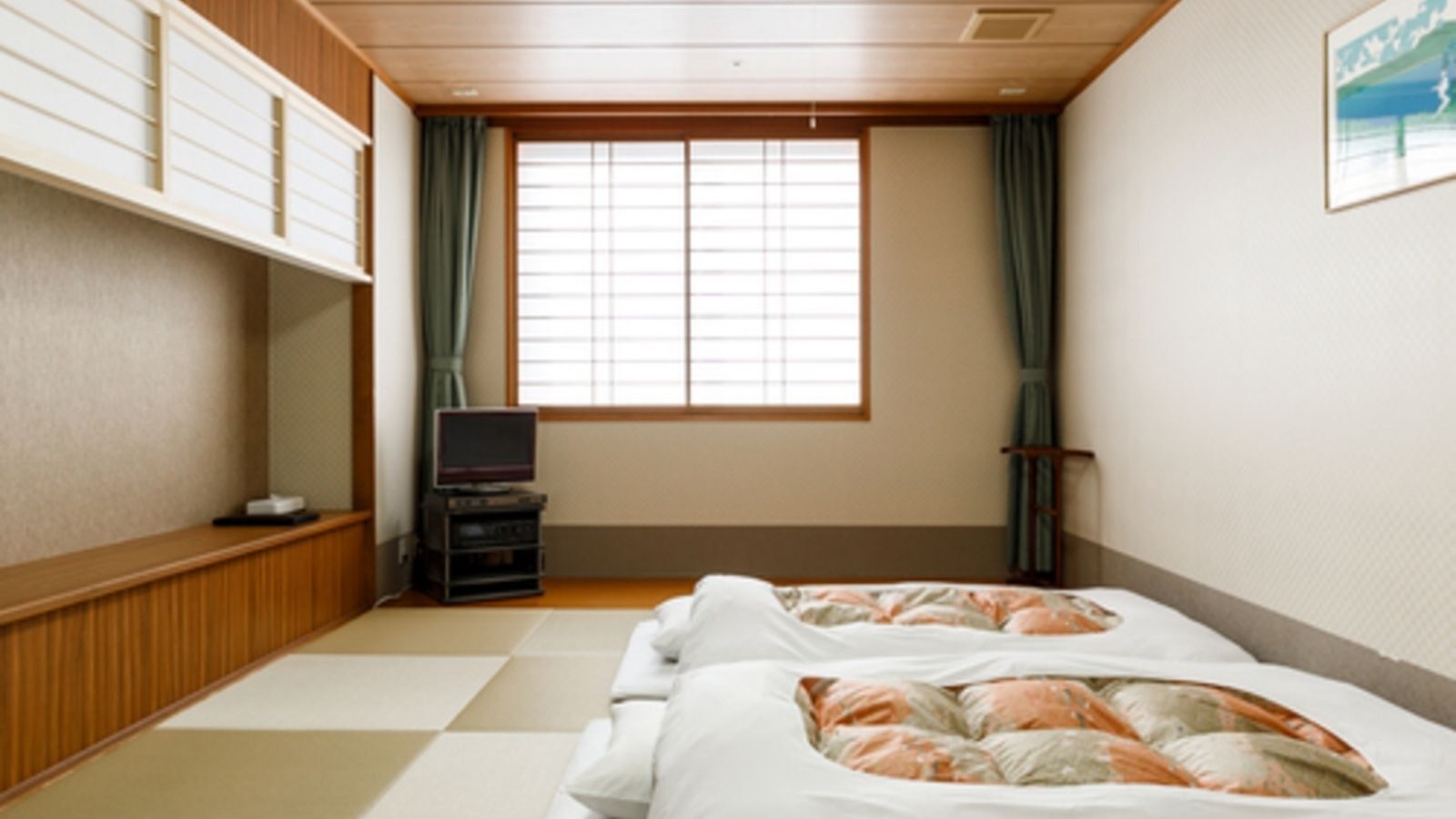 A room with two beds, a television, and a window with curtains.