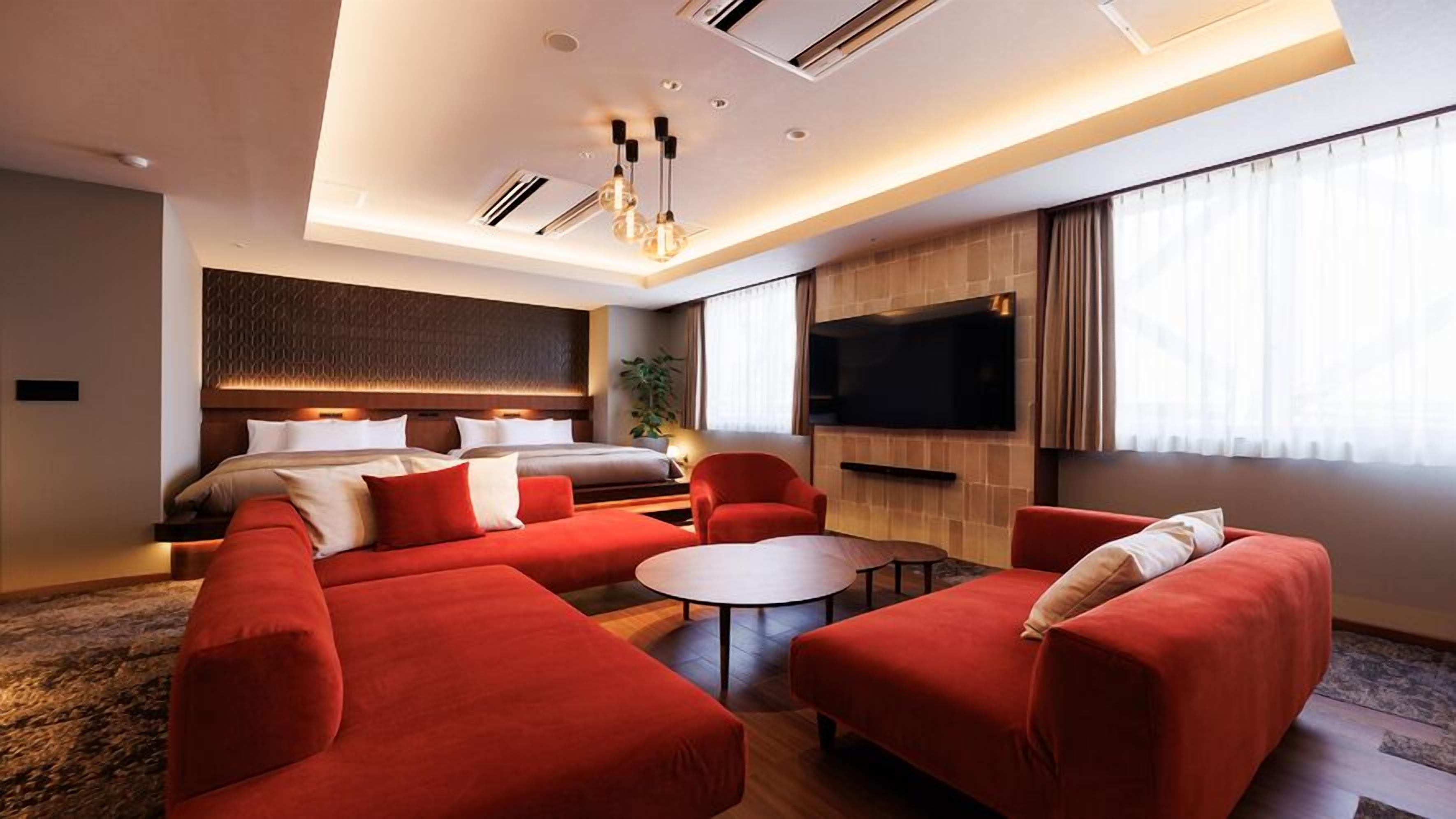 Una habitación de hotel moderna con una cama grande, un sofá, una mesita de café y un televisor.