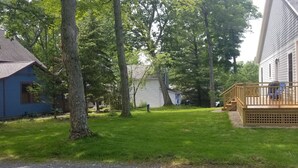 Une propriété résidentielle dotée d’une terrasse en bois, d’une pelouse et d’une maison bleue.