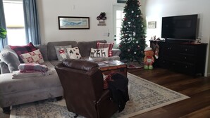 Un salon avec un canapé, un fauteuil et un sapin de Noël.