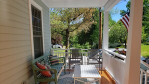 Une véranda avec un banc vert, une table et des chaises.
