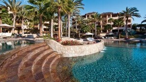 A resort pool with palm trees, lounge chairs, and a stone staircase leading into the water. - Esperanza Resort, PRIVATE POOL, JACUZZI PLUS 4 Bedroom, 4 1/2 Bath (Cabo San Lucas)