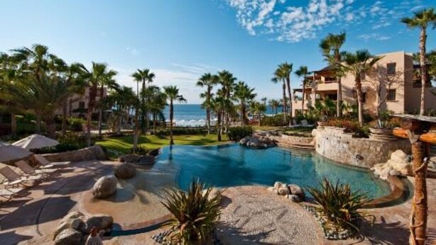 A resort pool area with palm trees, lounge chairs, and a view of the ocean. - Esperanza Resort, PRIVATE POOL, JACUZZI PLUS 4 Bedroom, 4 1/2 Bath (Cabo San Lucas)