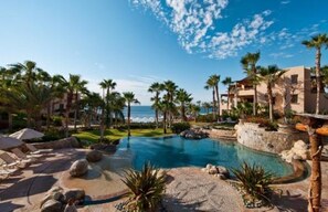 A resort pool area with palm trees, lounge chairs, and a view of the ocean. - Esperanza Resort, PRIVATE POOL, JACUZZI PLUS 4 Bedroom, 4 1/2 Bath (Cabo San Lucas)