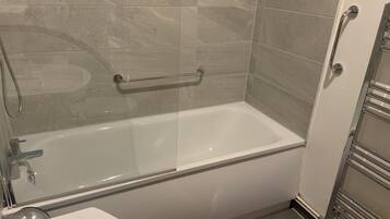 A modern bathroom with a bathtub, a shower, and a toilet.