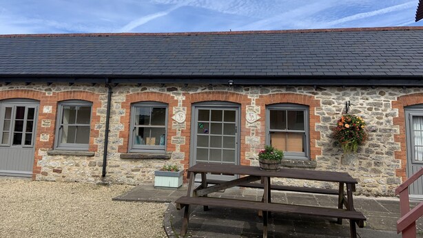 A stone building with arched windows and a picnic table in front. - Pretty stone cottage near the village of Pendoylan (Pendoylan)