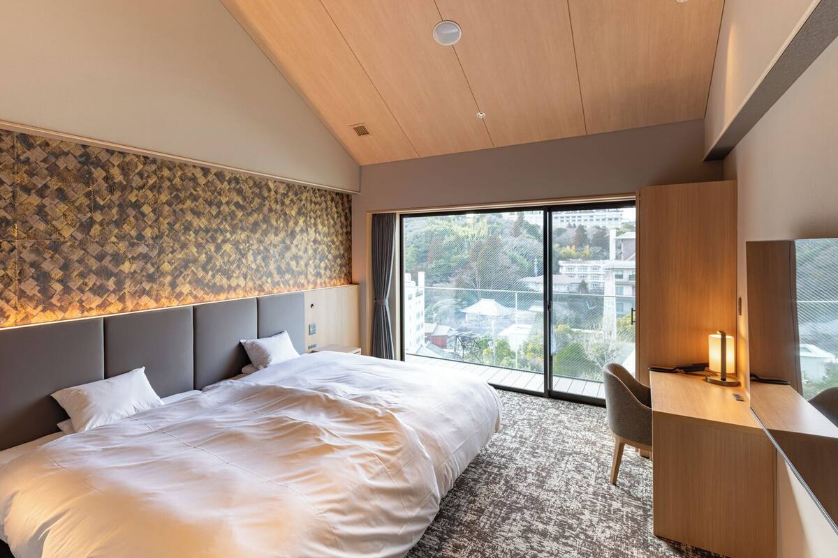 Un dormitorio moderno con una cama grande, un escritorio y vistas a la ciudad.