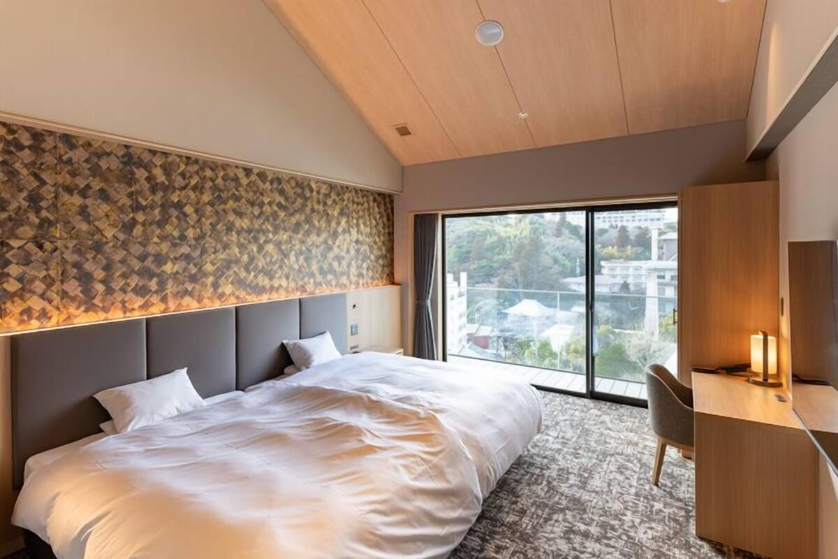 Una habitación de hotel moderna con una cama grande, un escritorio y vistas a la ciudad.