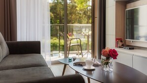 Ein modernes Wohnzimmer mit einer Couch, einem Couchtisch mit Tasse und Rosen sowie einem Fernseher an der Wand.