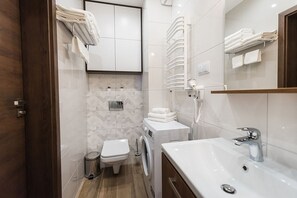 Une salle de bain moderne équipée d’un lave-linge, de toilettes et d’un lavabo.