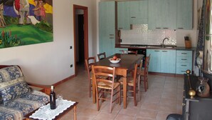 Ein Essbereich mit Holztisch und -stühlen, einem Gemälde an der Wand und einer Küche mit hellblauen Schränken.