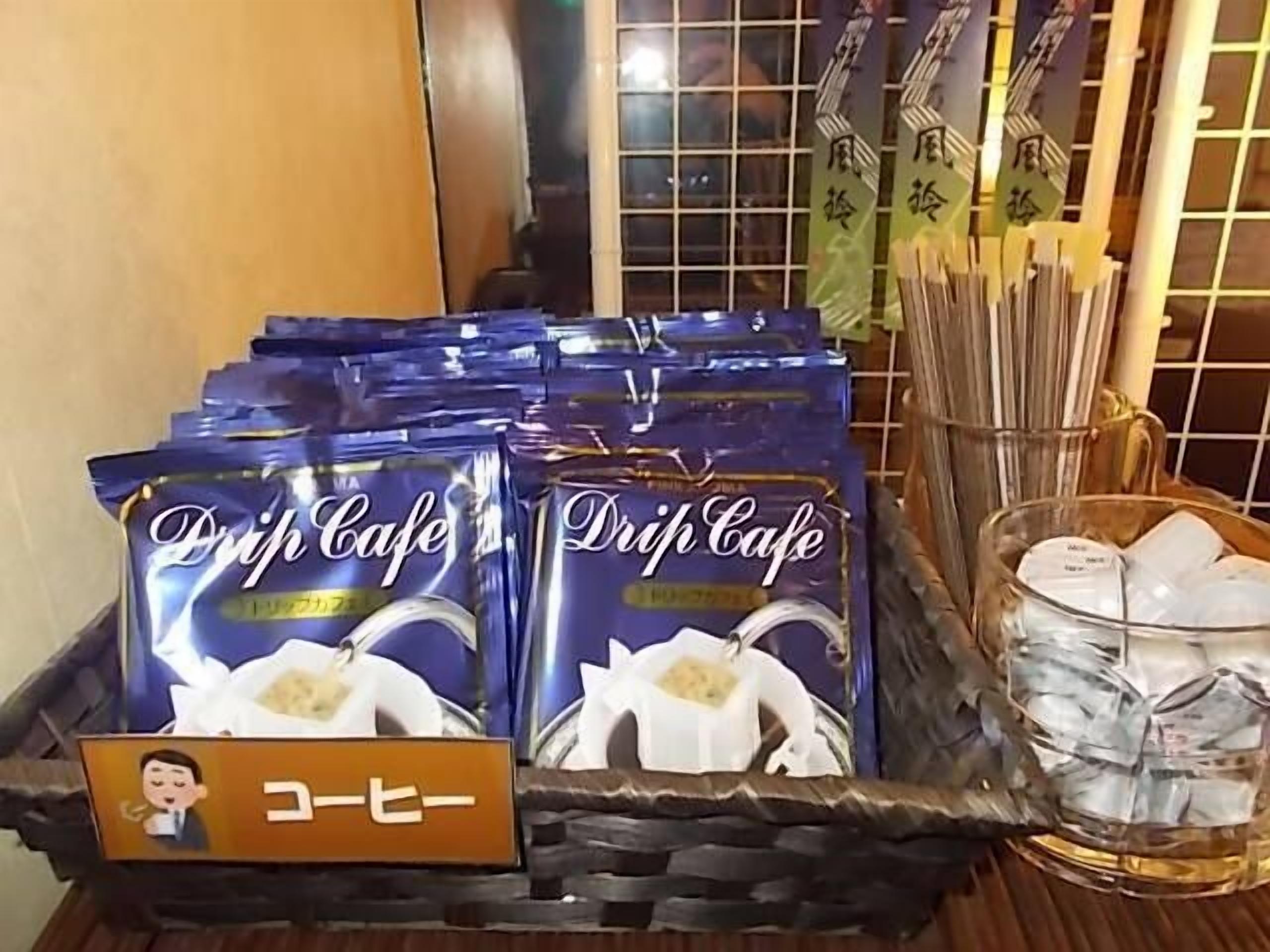 Un plateau contenant des sachets de café de la marque Drip Cafe, une enseigne avec un personnage de dessin animé et un panier de sachets de thé.