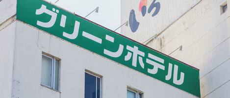 Un bâtiment avec une enseigne verte sur laquelle on peut lire « グリーンホテル » (Green Hotel).
