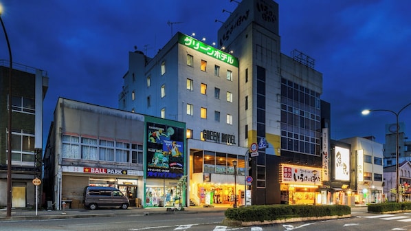 A hotel with a green sign, a sports store, and a ball park. - Mizusawa Green Hotel (Oshu)