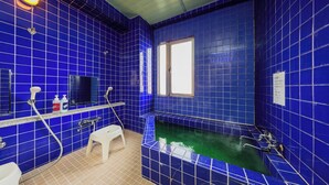 A bathroom with blue tiles, a bathtub, a window, a toilet, and a sink. - Mizusawa Green Hotel (Oshu)