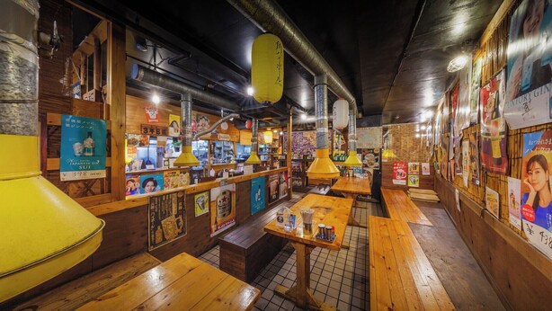 A restaurant interior with wooden tables and benches, hanging lanterns, and various posters on the walls. - Mizusawa Green Hotel (Oshu)