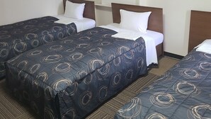 A hotel room with three beds, each with a dark blue bedspread featuring circular patterns. The room has a carpeted floor and a framed picture on the wall. - Mizusawa Green Hotel (Oshu)