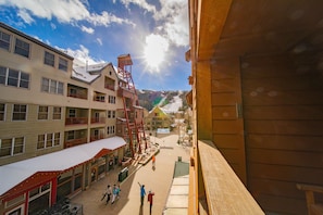Un hotel de varios pisos con balcones y una pista de esquí al fondo.