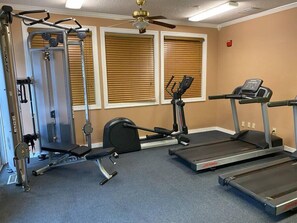 Un gimnasio con equipo de cardio, máquinas de pesas y una banca.