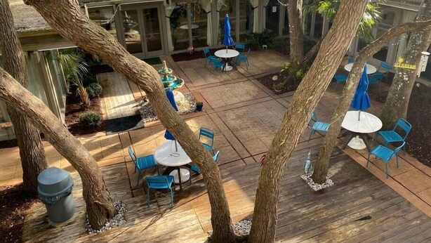 Un patio al aire libre con mesas y sillas, rodeado de árboles.