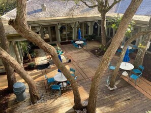 An outdoor patio area with tables and chairs, surrounded by trees. - Gorgeous One Bedroom Ocean Creek Condo (Myrtle Beach)