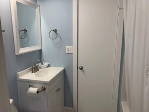 Un baño con lavamanos, espejo, toalleros y retrete.