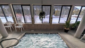 En indendørs swimmingpool med udsigt til et sneklædt landskab gennem store vinduer.