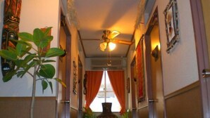 A hallway with a ceiling fan, a plant, and a window with curtains. - Guesthouse Sea Pappa (Naha)
