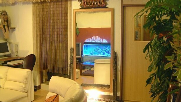 A living room with a sofa, a television, a computer, and a plant. - Guesthouse Sea Pappa (Naha)