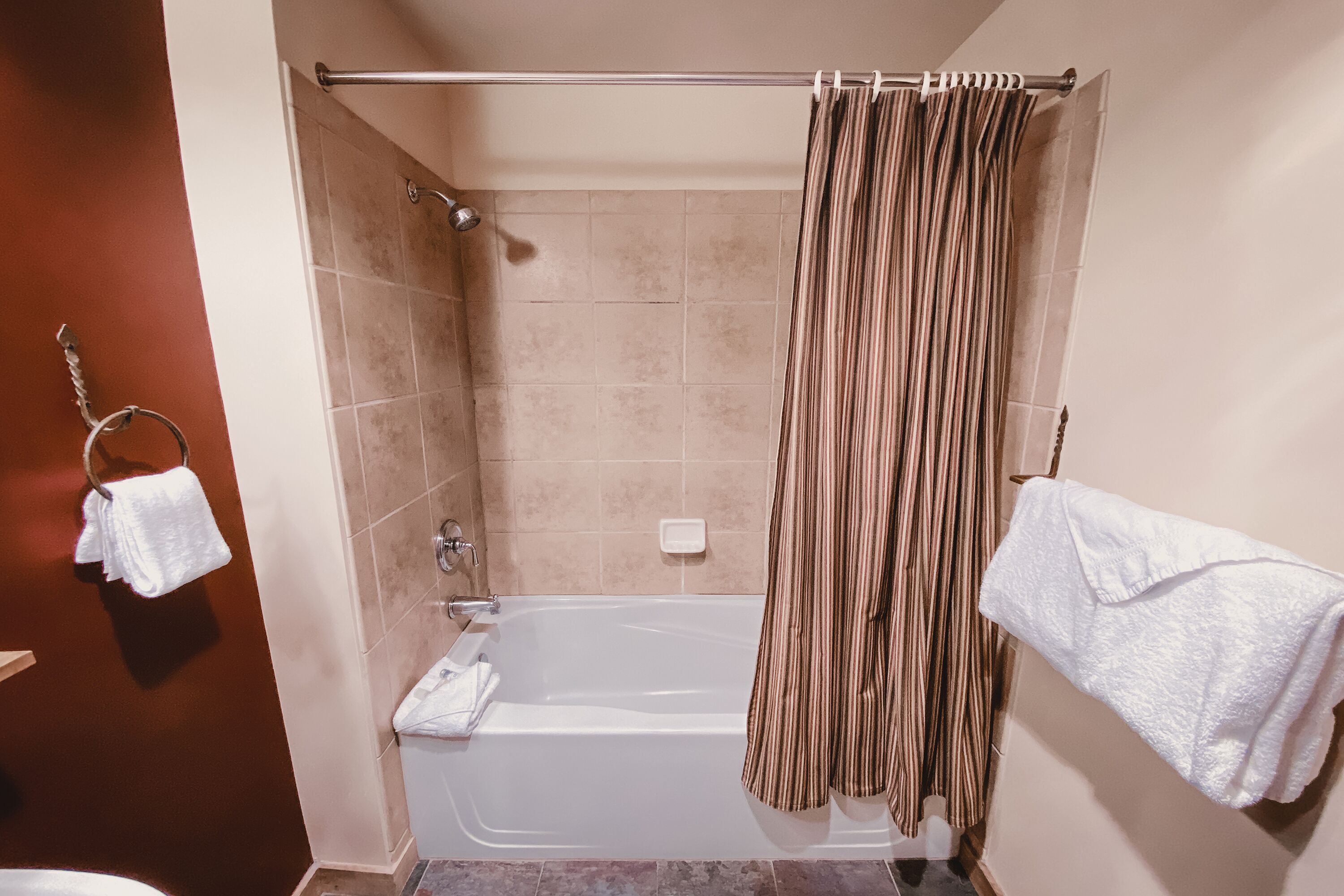 Ein Badezimmer mit einer Badewanne, einer Duschvorhang und zwei Handtüchern an einem Haken.