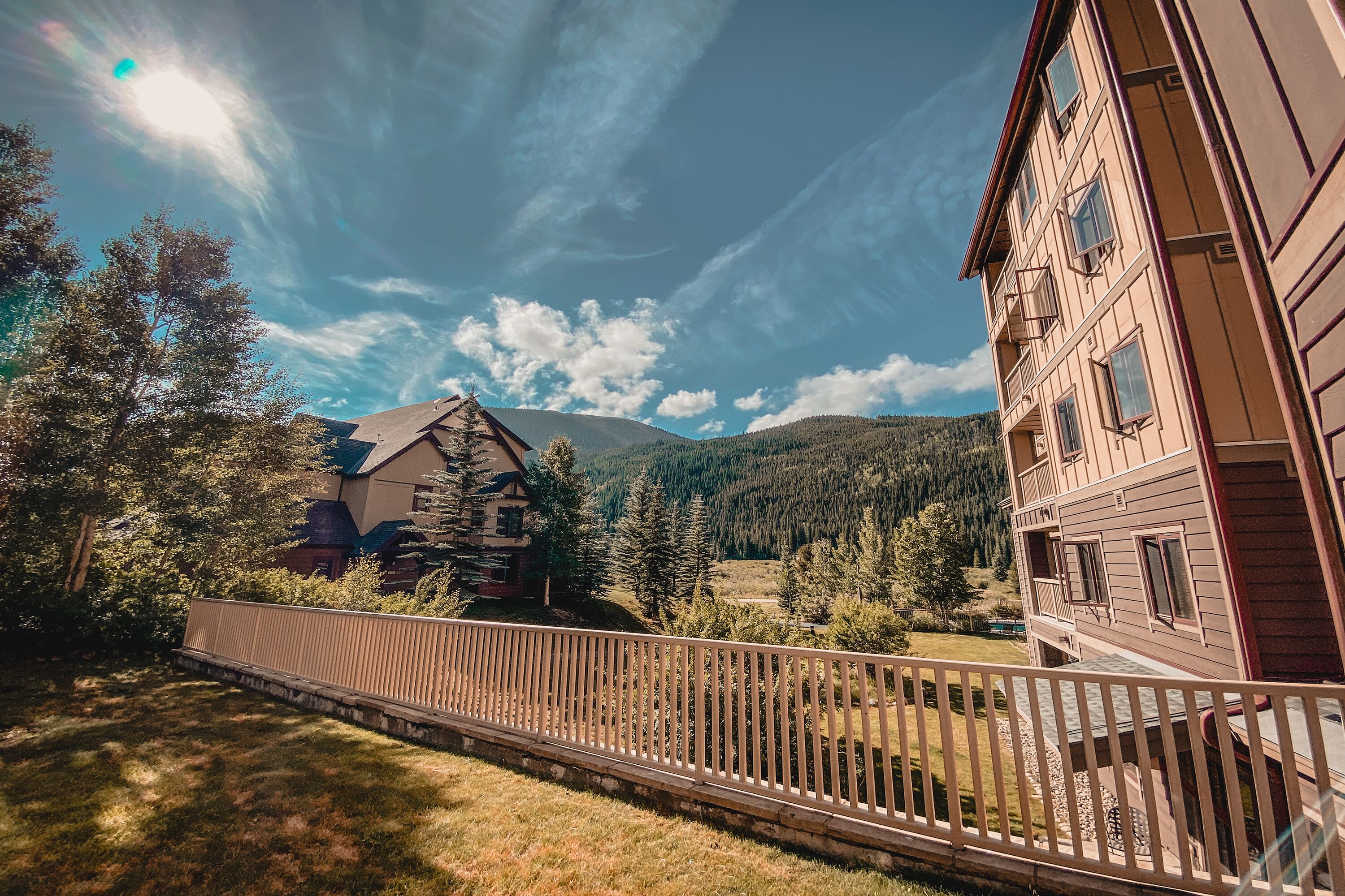 A wooden building with a balcony, surrounded by trees and mountains.