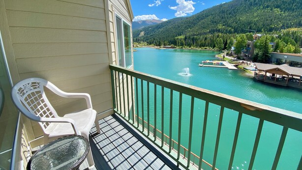 Un balcon donnant sur un lac turquoise, avec une chaise et une table.